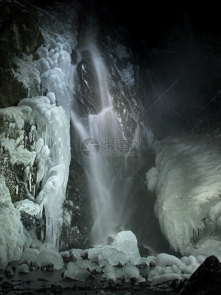 冬天的夜景冰柱和冰冷的巨石进入溪流图片