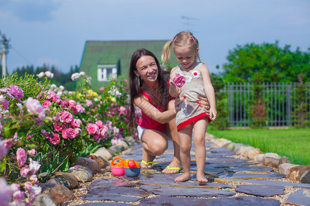 年轻母亲和她可爱的女儿在花园的夏季假图片