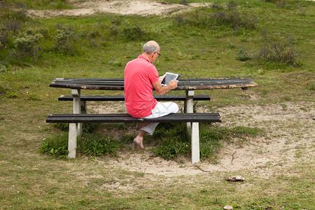 退休老人在草丘地貌的露天公园桌边休息图片