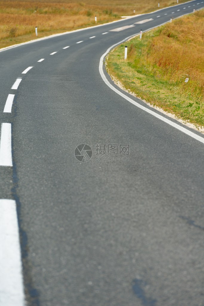 沥青路穿过田野夏日蓝天上的云彩图片