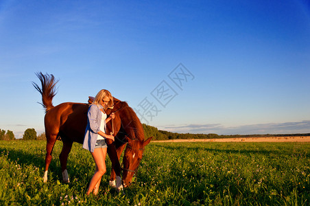 在田野里牵着马走路的年轻女孩图片