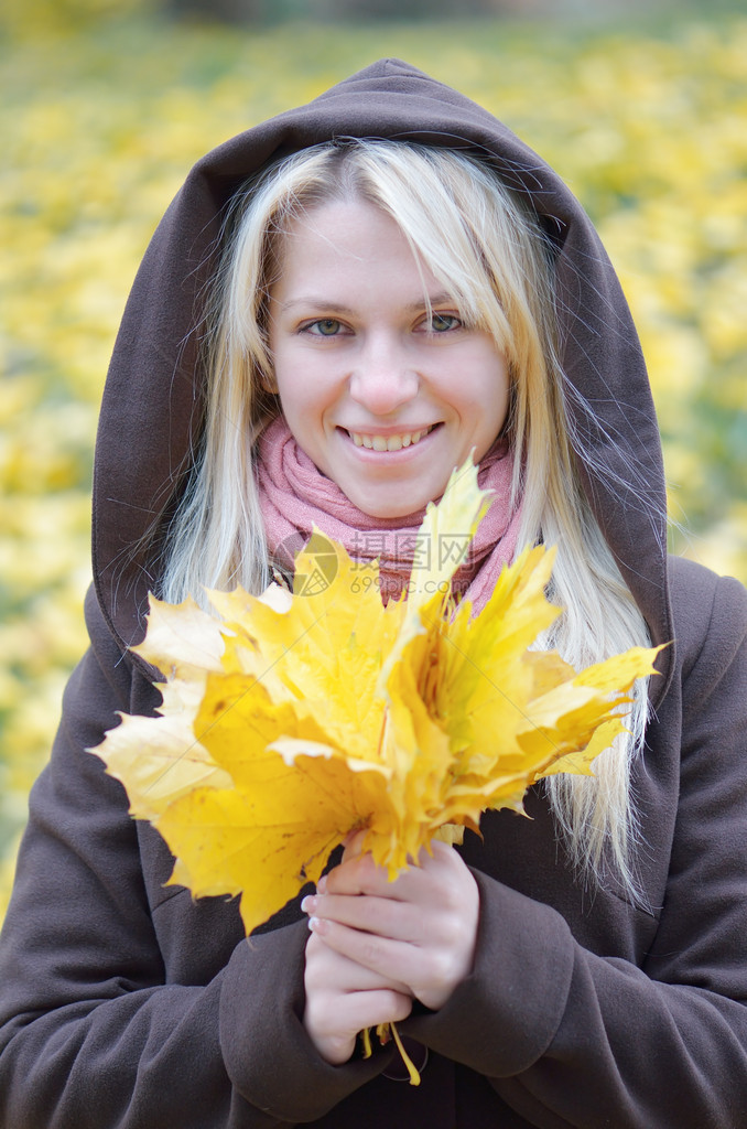 带着一束秋天枫叶的幸福女人图片