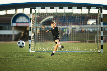小男孩在体育场踢足球图片