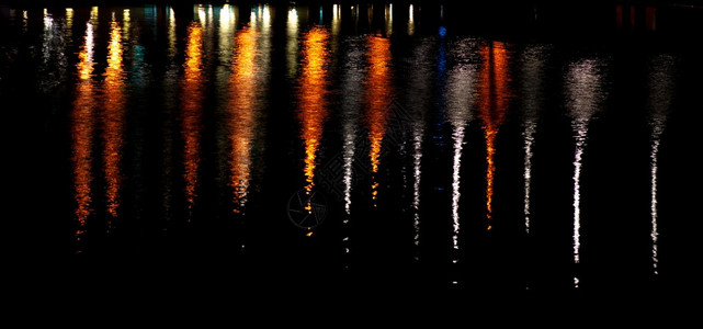 夜间黑暗水中城市灯光的反射图片