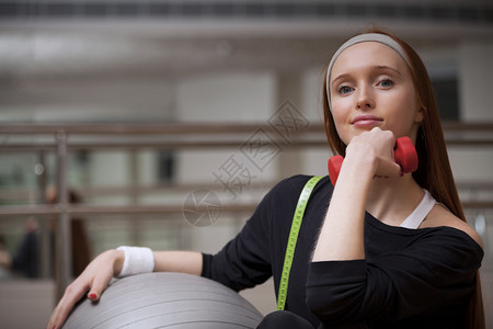 女人正坐着健身球重量和测量图片