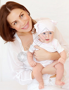 可爱年轻母亲抱着甜蜜新生儿在家幸福家庭爱与新生活概图片