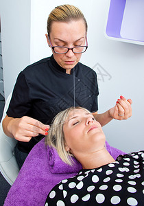 美容师在沙龙给金发女人做穿线脱毛程序图片