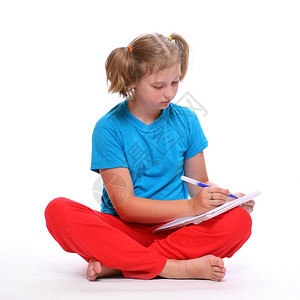 一个坐在地板上写字的漂亮小女孩的肖像图片