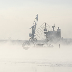 雾中的货船和起重机剪影图片