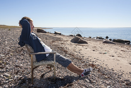 年轻人放松坐在海边的长凳图片