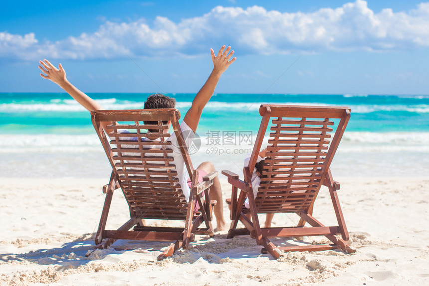 年幼父亲和女儿坐在沙椅上在海边举图片