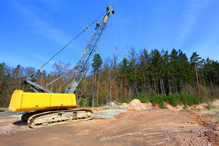 装载机挖土机位于受损的地貌景观中图片