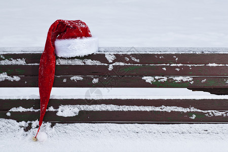 红色圣诞老人帽子在雪上盖图片