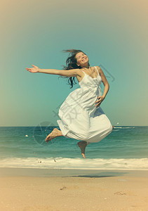 美丽的孕妇在海滩上跳跃照片以旧图片