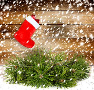白雪松树枝和红圣诞节靴子在老木墙图片