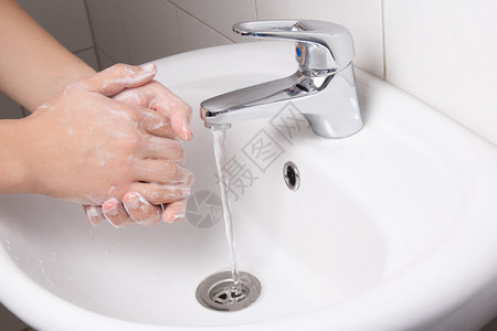 男人在白色浴室水槽里洗手图片