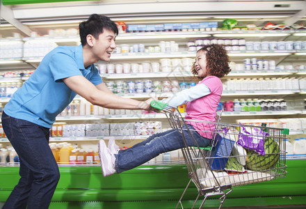 父亲在超市里把女儿推进购物图片