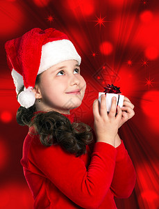 一个戴着圣诞帽和红色连衣裙的微笑小女孩的肖像图片