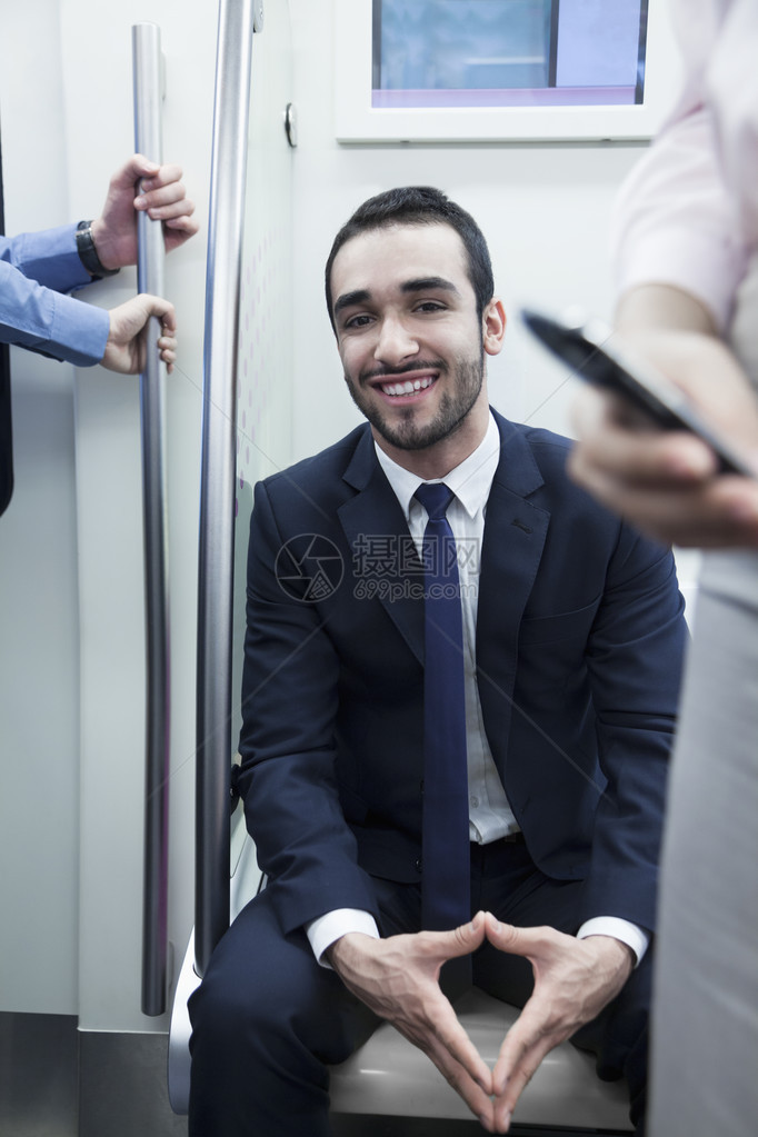 坐在地铁上看着摄影机的年轻笑图片