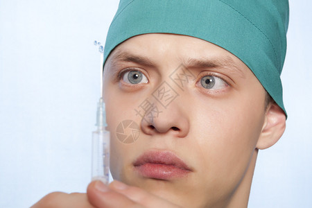 注射疫苗年轻医生在蓝背景图片