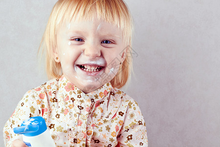 快乐的小女孩脸上涂着润肤霜图片