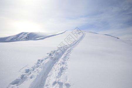 登山者在粉雪的山脊上滑雪上山图片
