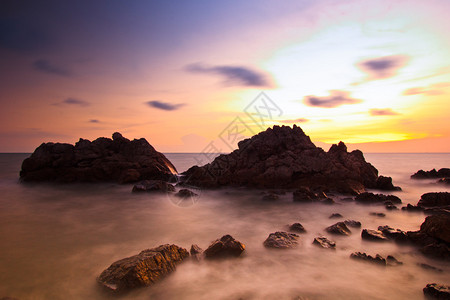 日落海浪线冲击海滩上的岩石图片