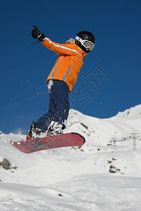 做跳跃的橙色夹克的滑雪板运动员图片