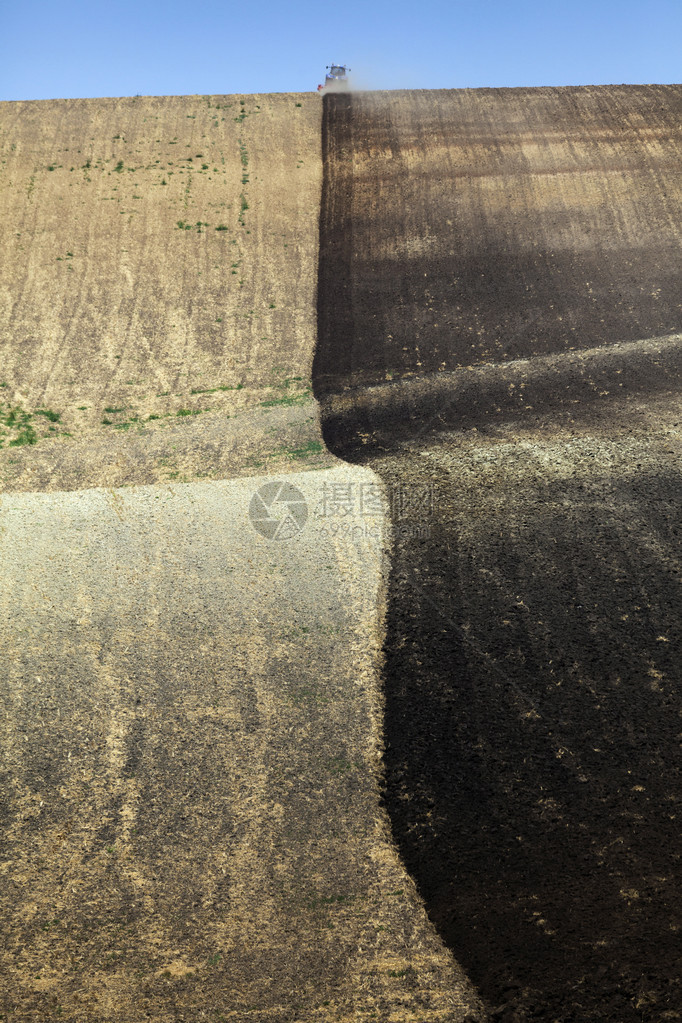 犁过的田沟里的拖拉机图片