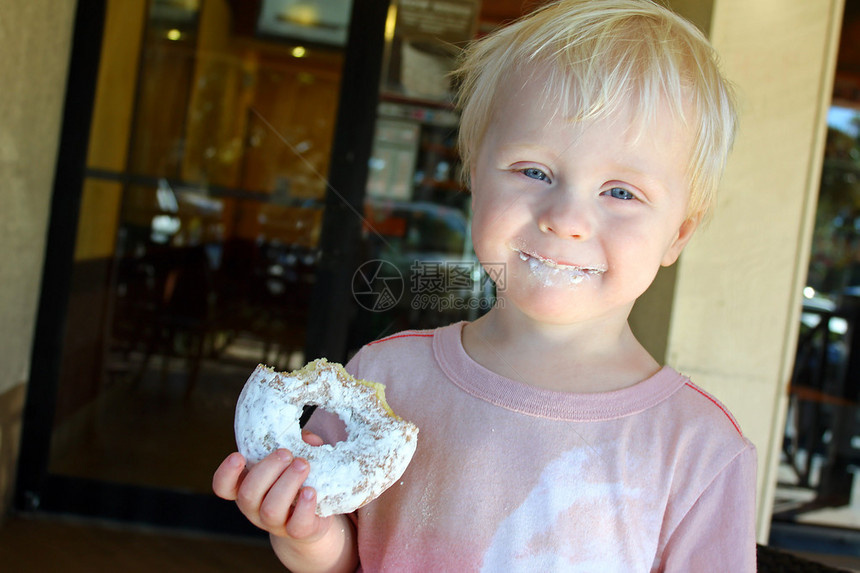 一个快乐的小孩站在咖啡店外面吃着奶粉胡发图片