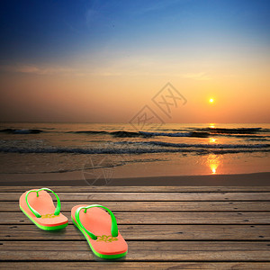 日出时沙滩上的木地板和拖鞋图片