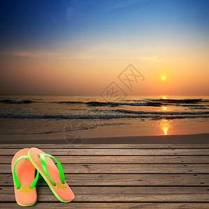 日出时沙滩上的木地板和拖鞋图片
