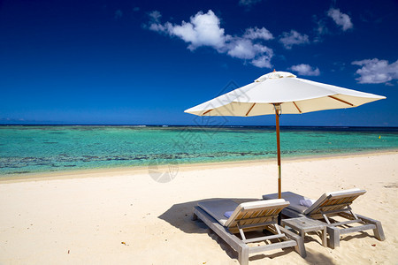 热带岛屿的白色沙滩配有躺椅和雨伞图片