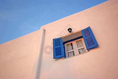 白色墙壁和蓝天上的复古蓝色窗户图片