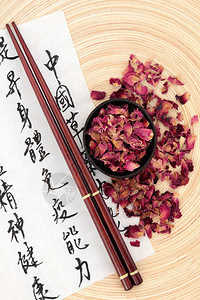 中草药玫瑰花瓣在宣纸上用国语书法文字描述了保持身心健康和平衡身体能背景图片