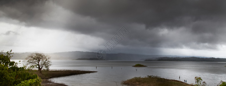 雨中地平线上的山湖全景图片