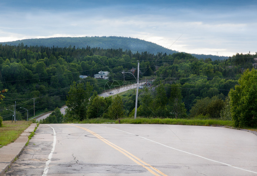 背景为绿色木头和山的沥青裂缝道路特写图片