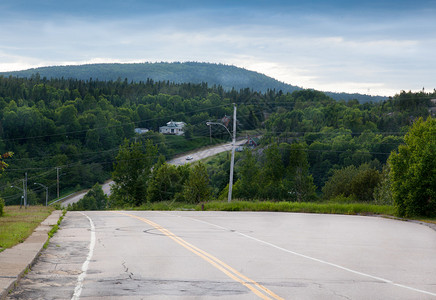 背景为绿色木头和山的沥青裂缝道路特写图片