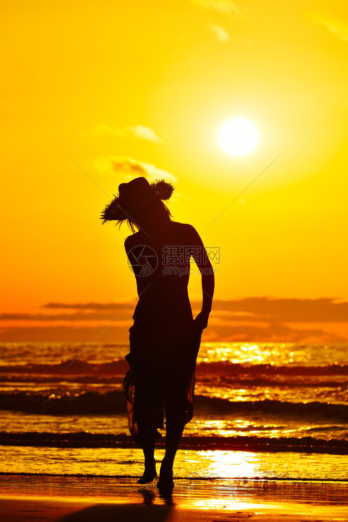 夏日傍晚海滩上的年轻女子剪影图片