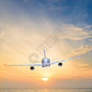 飞机在日落时在海面上飞行图片