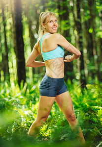在去森林里跑步之前伸展运动的女人积极健康的图片
