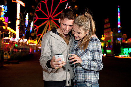 夫妇在晚上参观景点公园时使用智能手机图片