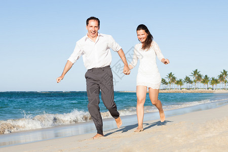 快乐情侣在海滩上奔跑时握图片