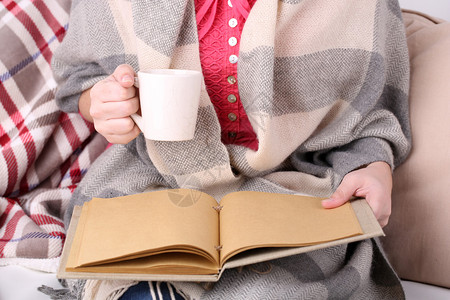 女人坐在沙发上看书喝咖啡或茶特写图片