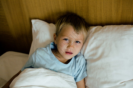 小可爱的男孩在床上眨图片