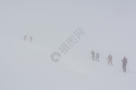 在高雾中攀升坡度的滑雪者斯图片