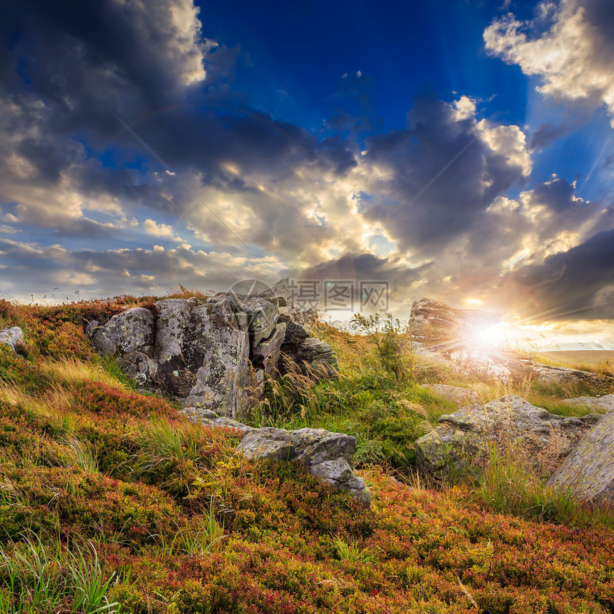山地景观在光束下的山坡上有石头的山谷在日落时在山顶图片