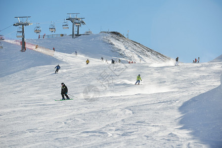 在阳光明媚的冬天滑雪者从山上滑下图片