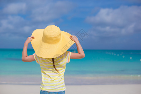 白色海滩上一个大黄草帽上的图片