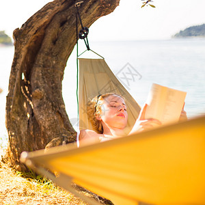 美丽的女孩躺在海边阅读图片